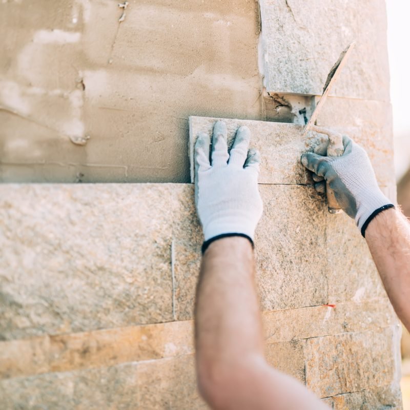 Mason,Worker,Installing,Stone,Tiles,On,Wall,On,Construction,Site